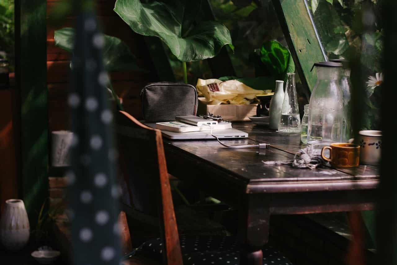 A peaceful indoor workspace featuring a laptop and coffee amidst lush greenery, perfect for creative work.